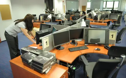 Kobieta przygotowuje stanowiska pracy w biurze. Czy to początek kariery, która okaże się najbardziej opłacalny zawód?