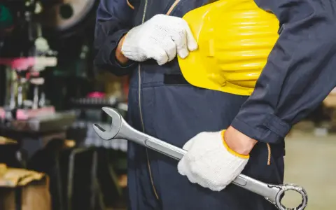 Obrero con casco amarillo y llave inglesa, listo para trabajar. Los epis son esenciales para su seguridad.