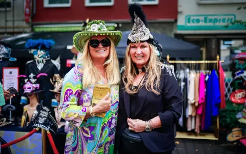 Zwei Frauen in bunten, auffälligen Outfits und Hüten genießen das Lindenthaler Sommerfest.