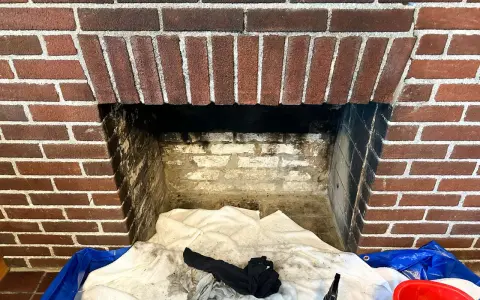 Camino in mattoni pronto per la pulizia. Il braciere è vuoto, ma c'è un allarme per la stufa a pellet.