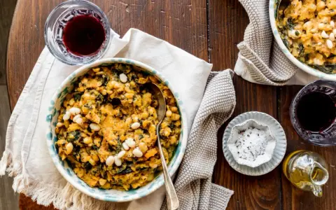 Un piatto rustico di fagioli e verdure, perfetto per scoprire cosa mangiare in Toscana. Accompagnato da vino rosso e olio d'oliva.