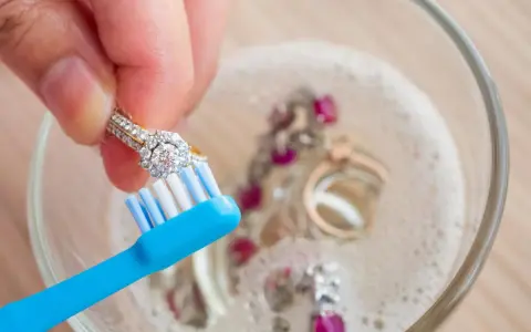 Limpia tu plata con bicarbonato y vinagre. Un anillo de diamantes se cepilla suavemente en un bol con joyas burbujeantes.
