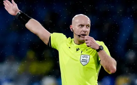 Sędzia piłkarski w żółtej koszulce z naszywką UEFA, dmucha w gwizdek. Zastanawiasz się, ile zarabia sędzia piłkarski?