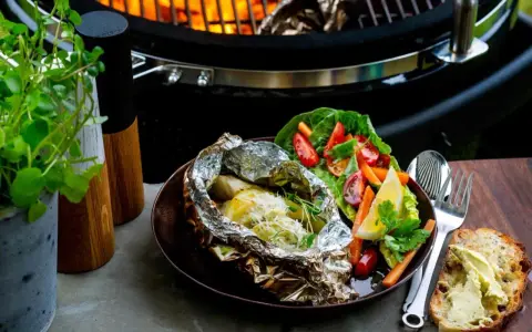 Fisk i folie på grillen, serverad med fräsch sallad och smörgås. En perfekt sommarmåltid att grilla fisk i folie.