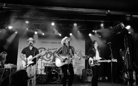 Band spelar på scen i Stockholm, med cowboyhattar och gitarrer. Kanske en hyllning till Fleetwood Mac Stockholm?