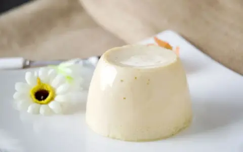 Delizioso budino fatto in casa, servito su un piatto bianco con un fiore decorativo.