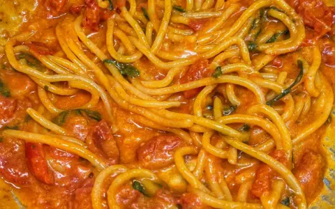 Spaghetti avvolti in un sugo cremoso di pomodoro e basilico, un invitante piatto di pasta allo scarpariello.