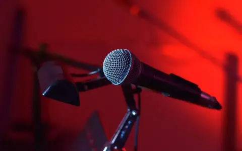 Mikrofon na statywie, gotowy do nagrania nastrojowego utworu w stylu trip hop. Czerwone światło tworzy atmosferę.