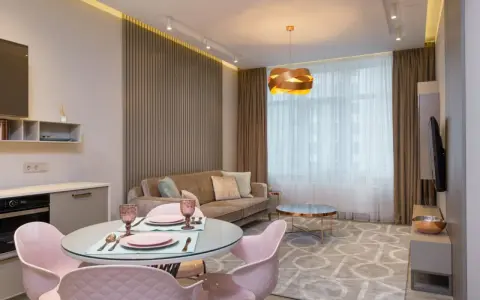 Nowoczesny salon z aneksem kuchennym po generalnym remoncie mieszkania 50m2. Jasne kolory, welurowa sofa i różowe krzesła tworzą przytulną atmosferę.