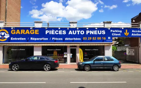 Garage avec enseigne bleue et jaune, deux voitures garées devant, sous un ciel bleu avec des nuages.