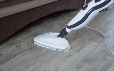 Mop parowy Vileda czyści drewnianą podłogę, wydzielając parę.