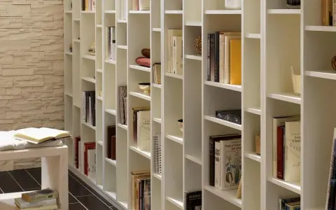 Eine weiße, modulare Bücherwand, perfekt für dein Projekt "Bibliothek selber bauen". Viele Bücher und Deko-Objekte sind ordentlich einsortiert.