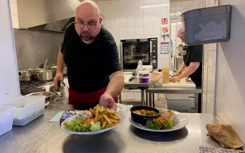 Un chef présente des assiettes de frites, salade et curry, des spécialités normandie.