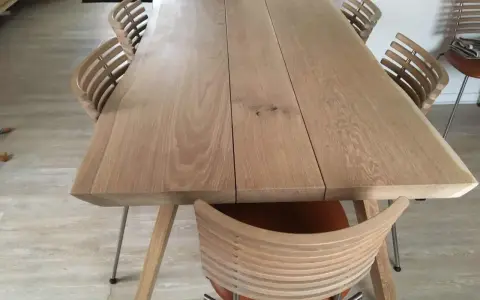 Oljat ekbord med ljusare träyta och moderna stolar med träribbor.