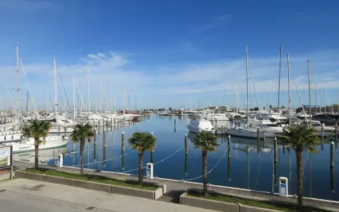Porto turistico di San Giuliano Mare, Rimini, con barche a vela e yacht ormeggiati in un mare calmo sotto un cielo azzurro.