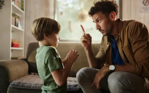 Un padre le dice no a su hijo, levantando el dedo índice en señal de advertencia. El niño escucha atentamente.