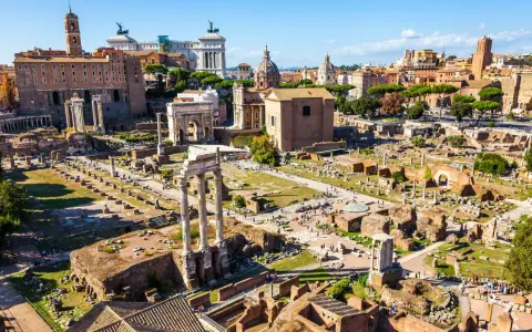 Antike Ruinen des Forum Romanum in Rom, 753 v. Chr. gegründet, mit Säulen, Bögen und Gebäuderesten unter blauem Himmel.