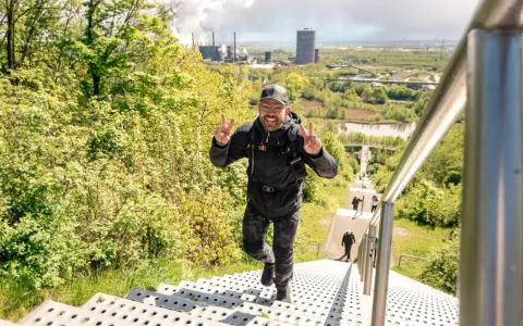 Glücklicher Mann erklimmt Treppen, genießt die Aussicht und verbrennt dabei Kalorien beim Wandern.