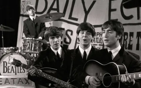Les Beatles, le groupe le plus connu au monde, jouent sur scène. John Lennon et Paul McCartney chantent, George Harrison joue de la basse, Ringo Starr est à la batterie.