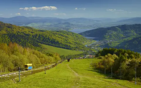 Widok na zielone beskid mały szczyty, jezioro i miasteczko. Kolejka krzesełkowa wjeżdża na górę.