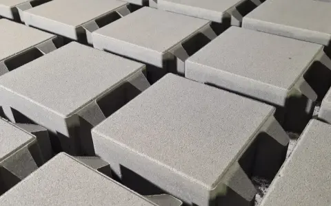 Szare, betonowe kostki brukowe ułożone w rzędach, gotowe do budowy ścieżki. Różne rodzaje kostki brukowej czekają na zastosowanie.