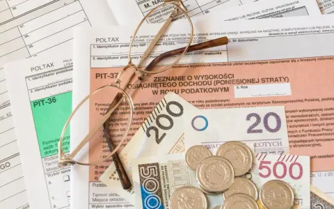 Okulary na dokumentach podatkowych PIT i pieniądzach. Zrozumienie, z czego wynika niedopłata podatku, wymaga analizy tych dokumentów.