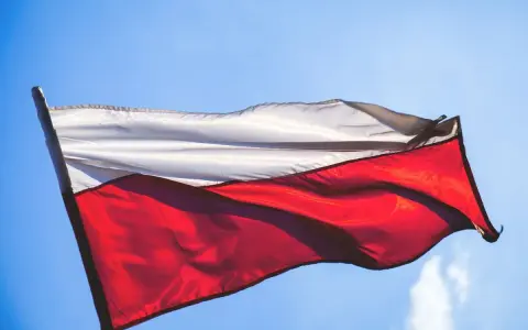 Flaga Polski, biało-czerwona, powiewa na tle błękitnego nieba.