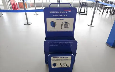 Niebieska miarka bagażu podręcznego British Airways na lotnisku. Sprawdź wymiary swojego bagażu kabinowego.