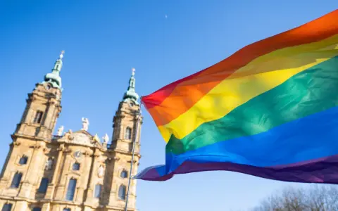Regenbogenfahne weht vor evangelischer Kirche. Ein Zeichen für Akzeptanz und Vielfalt, das die Botschaft der evangelischen Kirche LGBT widerspiegelt.