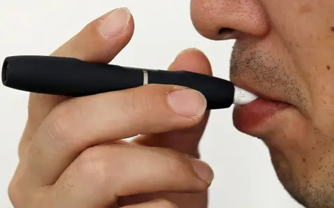 Persona usa un dispositivo IQOS. Las opiniones médicas sobre IQOS son variadas, pero este dispositivo calienta tabaco en lugar de quemarlo.