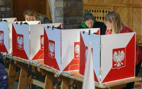 Kobiety głosują w wyborach do sejmu. Kabiny wyborcze ozdobione są godłem Polski.