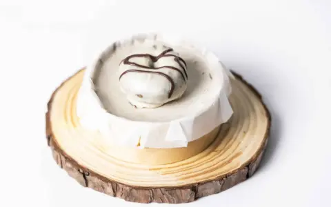 Deliciosa tarta de oro, cubierta de blanco y decorada con chocolate. Presentada sobre una base de madera rústica.