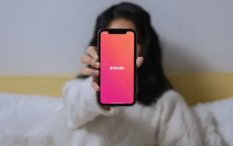 Osoba trzyma telefon z widocznym logo Tindera. Chcesz wiedzieć, jak sprawdzić, czy ktoś ma Tindera?