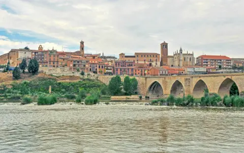 Un pintoresco pueblo con un puente de piedra sobre un río, ideal para visitar si buscas pueblos bonitos cerca de Valladolid.