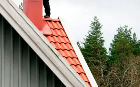 Person på taket vid skorstenen, en del av en sotarutbildning.