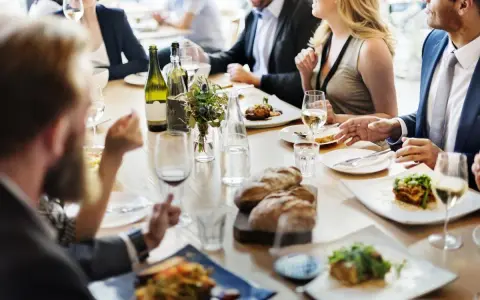 Un dîner sympa entre amis, avec des plats appétissants, du pain frais et du vin blanc sur une table en bois.