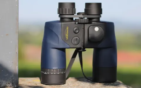 Ein blaues Omegon Fernglas 7x50, dessen Bedeutung in der Vergrößerung und Objektivgröße liegt, steht auf einem Stein.