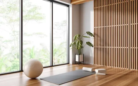 Ett ljust och luftigt yogarum hemma med stora fönster, en yogamatta, boll och en grön växt.