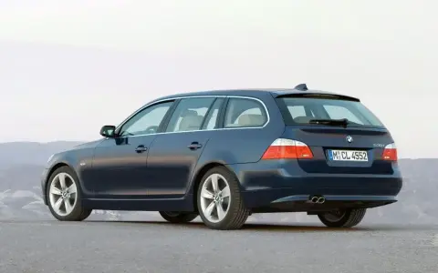 Granatowe BMW E61, kombi, stoi na pustej drodze.