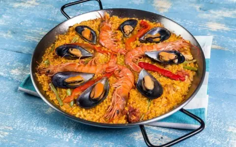 Paella mixta con gambas y mejillones, un festín de sabores mediterráneos en una paellera.