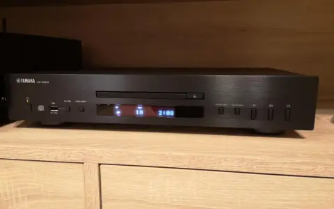 Czarny odtwarzacz CD Yamaha CD-S303 na drewnianej półce, gotowy do testu. Wyświetlacz pokazuje utwór 10 z 2:08.