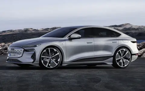 Silberner Audi A4 e-tron, ein elegantes Elektroauto, steht vor einer felsigen Küstenlandschaft.