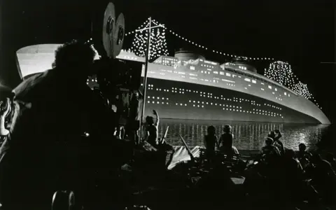 Sul set di Amarcord, una nave illuminata di notte, con cinepresa in primo piano.