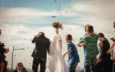 Para młoda w chmurze konfetti, dron filmuje ich wyjście. Stylowe zakończenie imprezy, jak zakończyć stylową imprezę efektownym wyjściem pary lub jubilata.