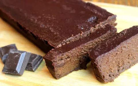 Un délicieux gâteau chocolat compote, coupé en tranches, avec des carrés de chocolat à côté.