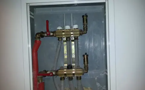 Widoczny zawór RTL na powrocie systemu ogrzewania podłogowego. Metalowa obudowa skrywa skomplikowaną instalację hydrauliczną.