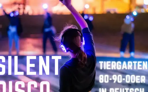 Silent Disco Berlin im Tiergarten. Leute tanzen mit leuchtenden Kopfhörern im Dunkeln.