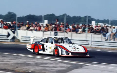Der Porsche 935 "Moby Dick" rast auf der Rennstrecke, die Zuschauer jubeln.