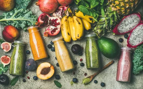 Färgglada smoothies i flaskor, omgivna av färsk frukt och grönsaker. En visuell påminnelse om vad betyder detox för kroppen.