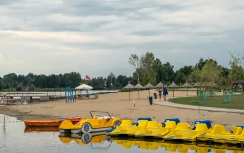 Żółte rowerki wodne i łódki czekają na plaży. Idealne miejsce na wypoczynek, jak na Mazurach blisko Warszawy.